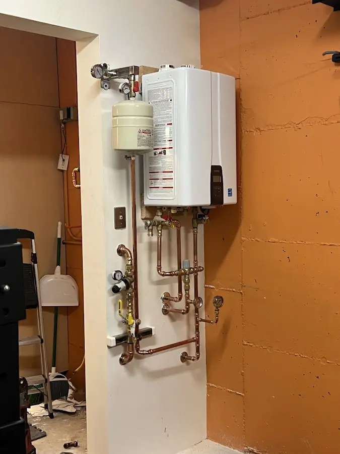 Plumbing technician inspecting water heater connections in Oradell